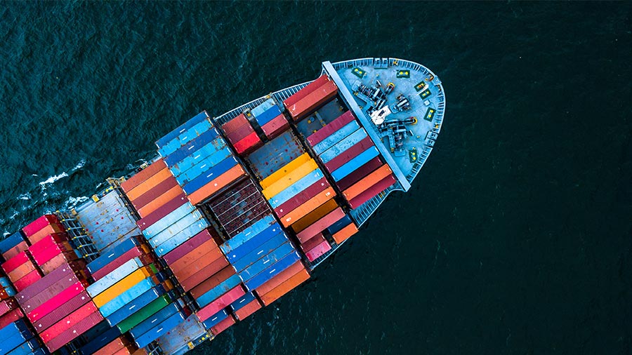 An aerial view of a large cargo ship carrying colorful shipping containers, representing international trade, global logistics, and streamlined supply chain management solutions.