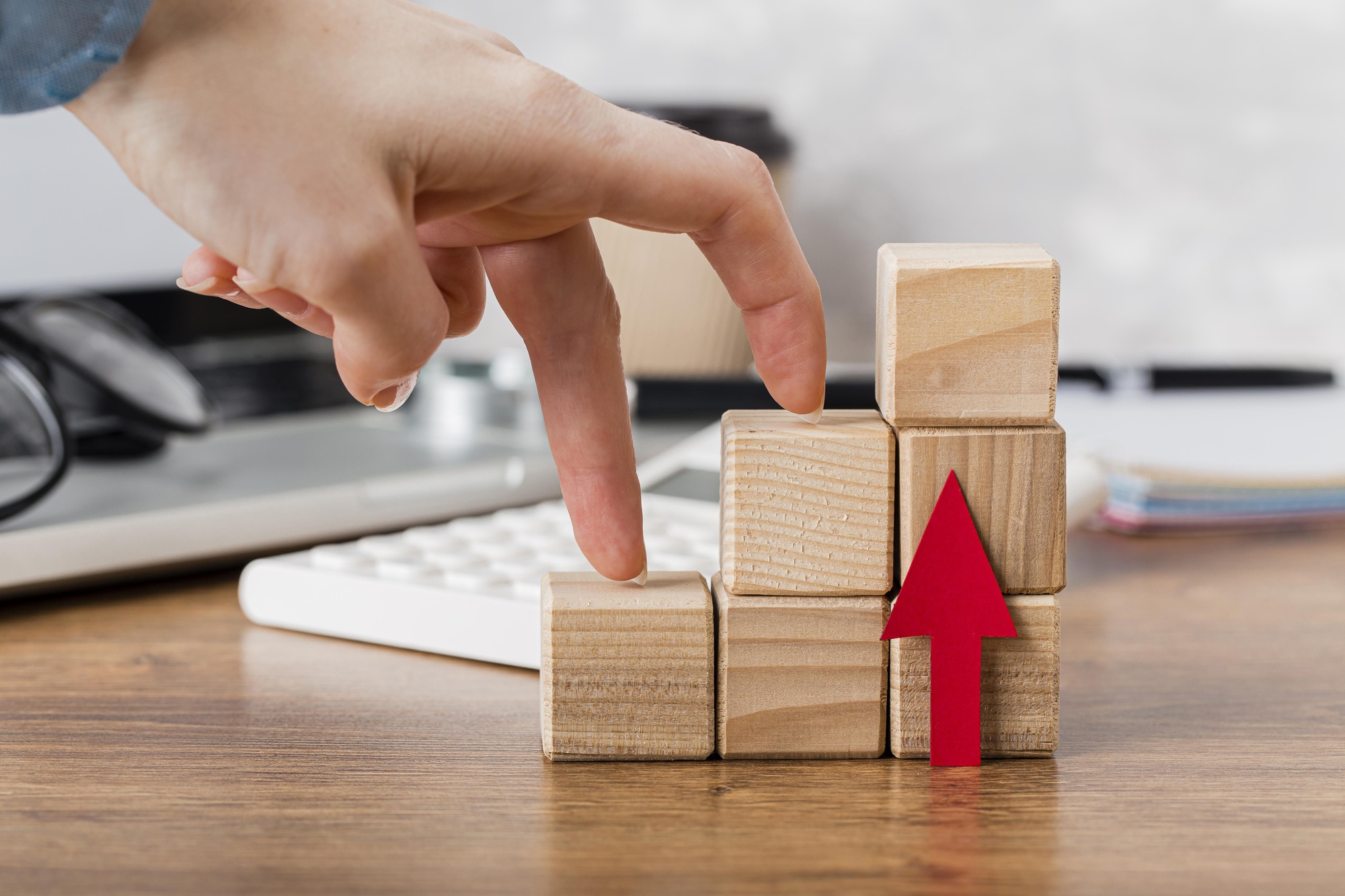 A hand stepping up wooden blocks in a staircase formation, representing business growth, progress, and strategic development.